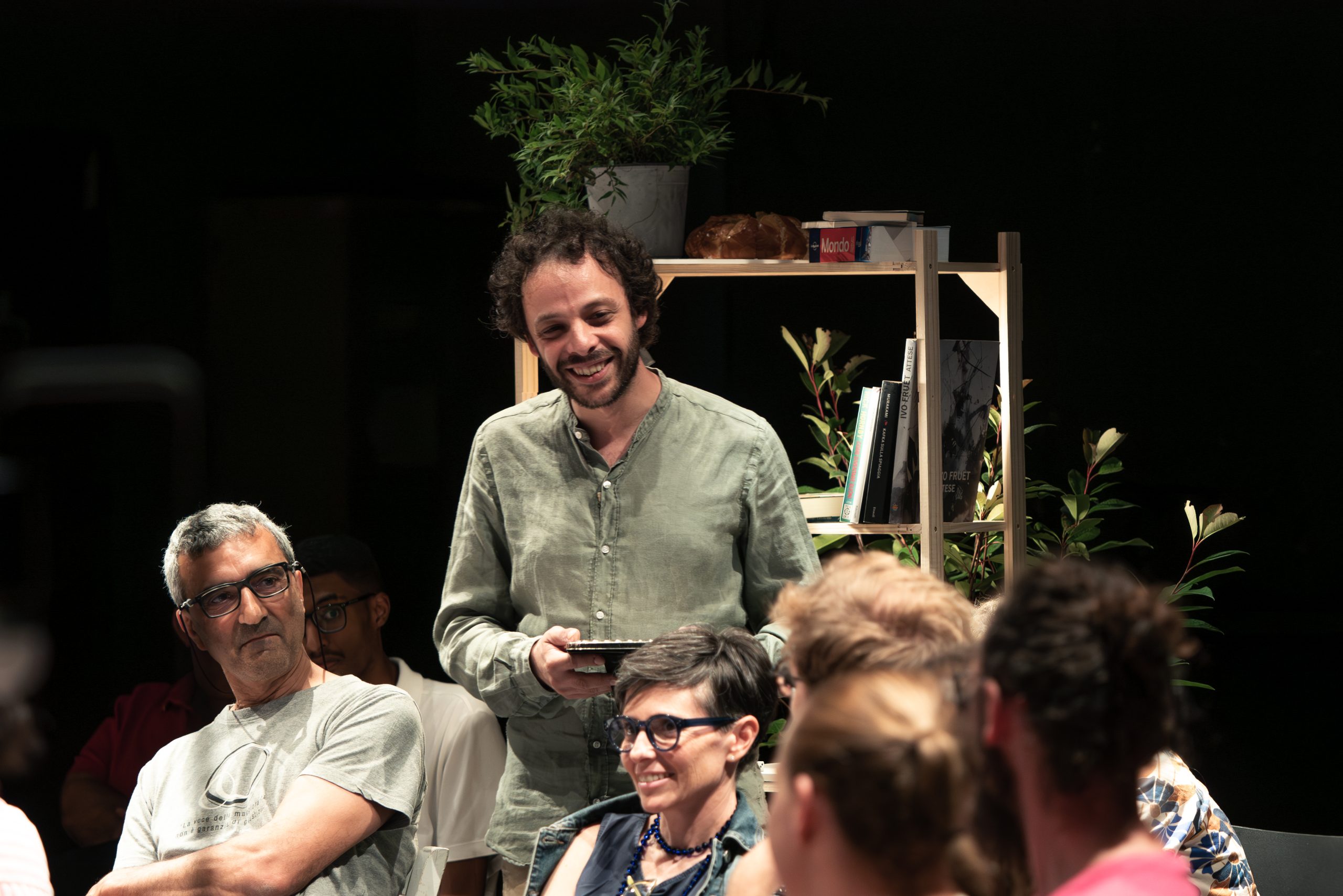 L'attore Nicola Borghesi, circondato dal pubblico, sorregge una cornice e sorride.