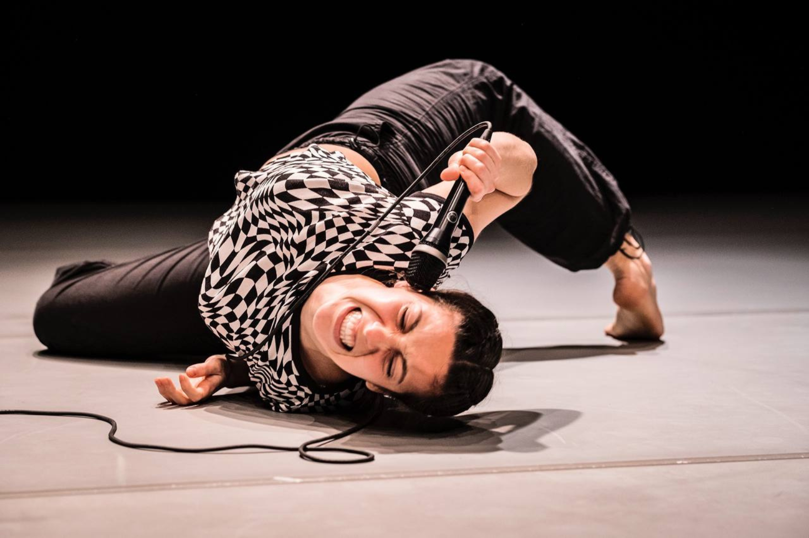 In foto, la performer Annalisa Limardi si contorce a terra tenendo un microfono all'orecchio