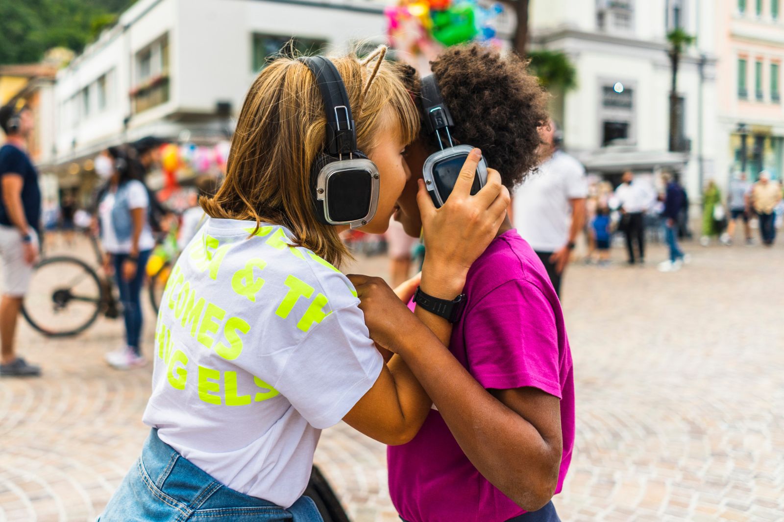 In foto, due bambine indossano grandi cuffie per ascoltare la musica